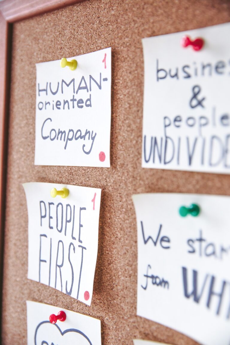 white papers with captions "human oriented company" and "people first" pinned to a board